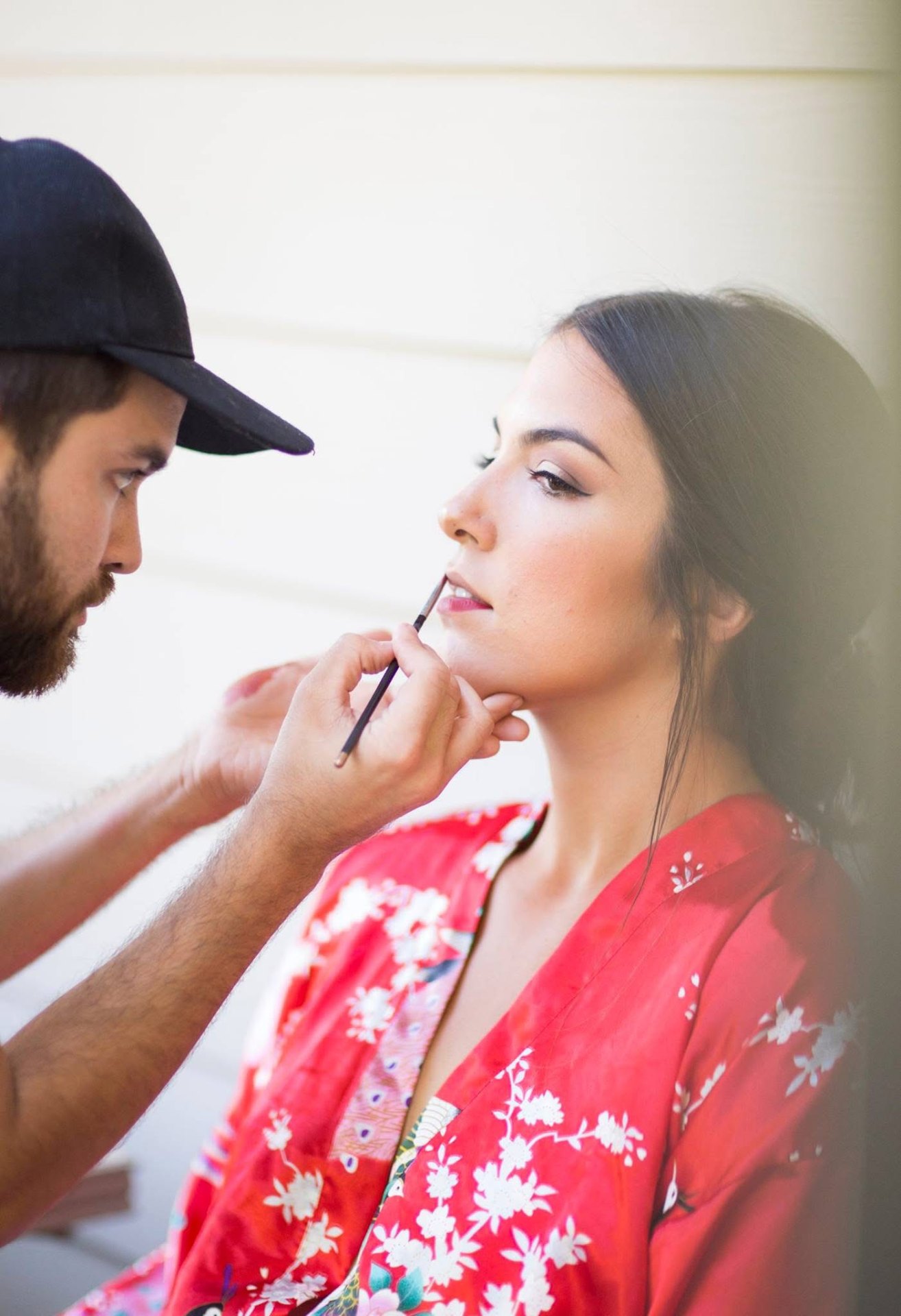 Carwin Brice applying lip color on model in red floral robe